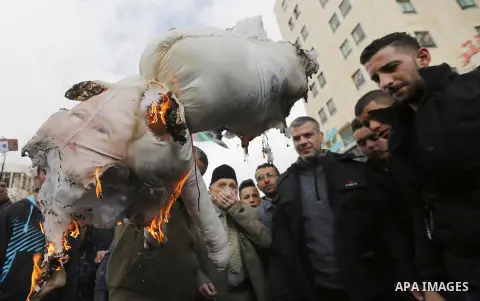 Palestinian protestors burn stuffed pillows in the shape of a pig and bearing an image of Israeli President Benjamin Netanyahu during a demonstration in the West Bank town of Hebron on December 13, 2017. Photo by Wisam H...