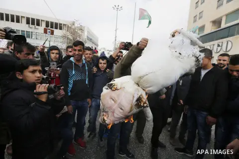 Palestinian protestors burn stuffed pillows in the shape of a pig and bearing an image of Israeli President Benjamin Netanyahu during a demonstration in the West Bank town of Hebron on December 13, 2017. Photo by Wisam H...