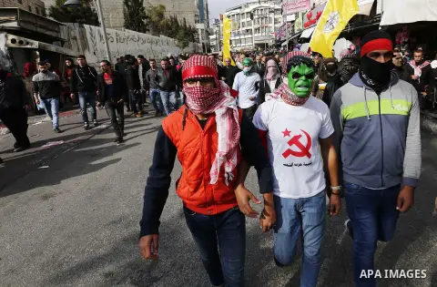 Palestinian protestors wave their national flag and shout slogans during a demonstration in the West Bank town of Hebron on December 13, 2017. Photo by Wisam Hashlamoun