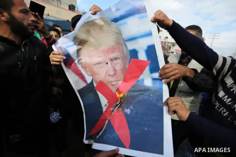 Palestinians burn posters depicting U.S. President Donald Trump during a protest against US President Donald Trump's decision to recognise Jerusalem as the capital of Israel, in al-Bureij in the central of Gaza strip, on...