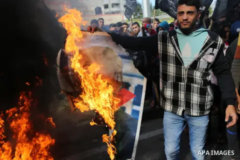 Palestinians burn posters depicting U.S. President Donald Trump during a protest against US President Donald Trump's decision to recognise Jerusalem as the capital of Israel, in al-Bureij in the central of Gaza strip, on...