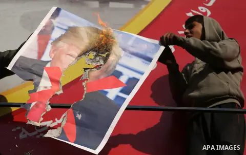 Palestinians burn posters depicting U.S. President Donald Trump during a protest against US President Donald Trump's decision to recognise Jerusalem as the capital of Israel, in al-Bureij in the central of Gaza strip, on...