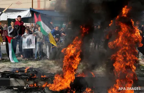 Palestinians burn posters depicting U.S. President Donald Trump during a protest against US President Donald Trump's decision to recognise Jerusalem as the capital of Israel, in al-Bureij in the central of Gaza strip, on...