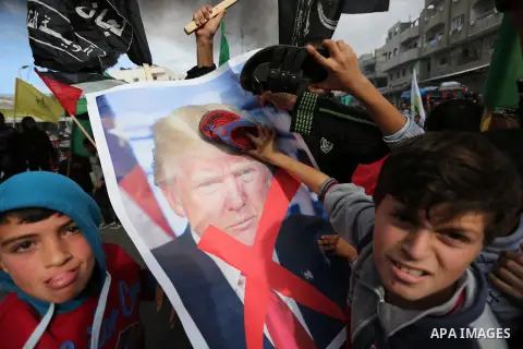Palestinians hit with slippers a poster depicting U.S. President Donald Trump during a protest against US President Donald Trump's decision to recognise Jerusalem as the capital of Israel, in al-Bureij in the central of...