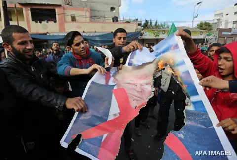 Palestinians burn posters depicting U.S. President Donald Trump during a protest against US President Donald Trump's decision to recognise Jerusalem as the capital of Israel, in al-Bureij in the central of Gaza strip, on...