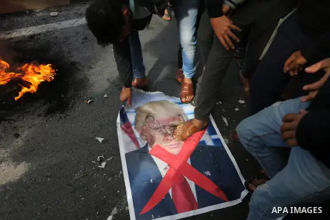 Palestinians burn posters depicting U.S. President Donald Trump during a protest against US President Donald Trump's decision to recognise Jerusalem as the capital of Israel, in al-Bureij in the central of Gaza strip, on...