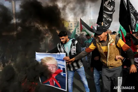 Palestinians burn posters depicting U.S. President Donald Trump during a protest against US President Donald Trump's decision to recognise Jerusalem as the capital of Israel, in al-Bureij in the central of Gaza strip, on...