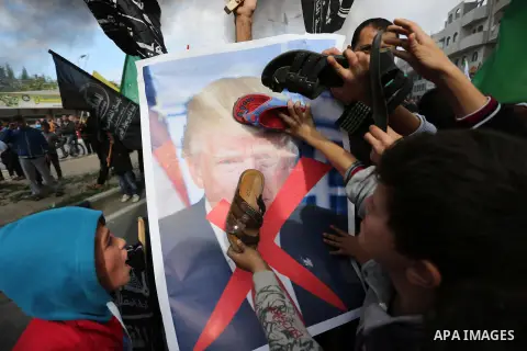 Palestinians hit with slippers a poster depicting U.S. President Donald Trump during a protest against US President Donald Trump's decision to recognise Jerusalem as the capital of Israel, in al-Bureij in the central of...