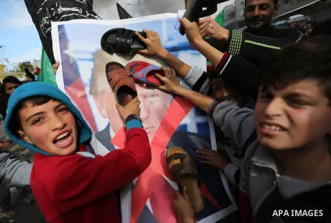 Palestinians hit with slippers a poster depicting U.S. President Donald Trump during a protest against US President Donald Trump's decision to recognise Jerusalem as the capital of Israel, in al-Bureij in the central of...