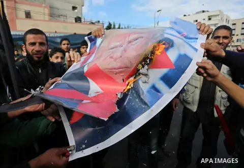 Palestinians burn posters depicting U.S. President Donald Trump during a protest against US President Donald Trump's decision to recognise Jerusalem as the capital of Israel, in al-Bureij in the central of Gaza strip, on...
