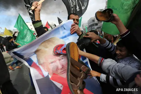 Palestinians hit with slippers a poster depicting U.S. President Donald Trump during a protest against US President Donald Trump's decision to recognise Jerusalem as the capital of Israel, in al-Bureij in the central of...