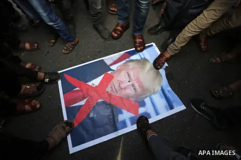 Palestinians burn posters depicting U.S. President Donald Trump during a protest against US President Donald Trump's decision to recognise Jerusalem as the capital of Israel, in al-Bureij in the central of Gaza strip, on...