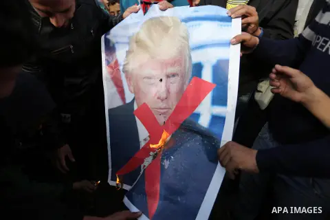 Palestinians burn posters depicting U.S. President Donald Trump during a protest against US President Donald Trump's decision to recognise Jerusalem as the capital of Israel, in al-Bureij in the central of Gaza strip, on...