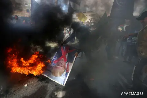 Palestinians burn posters depicting U.S. President Donald Trump during a protest against US President Donald Trump's decision to recognise Jerusalem as the capital of Israel, in al-Bureij in the central of Gaza strip, on...