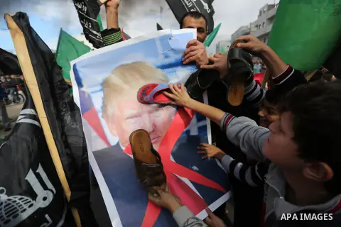 Palestinians hit with slippers a poster depicting U.S. President Donald Trump during a protest against US President Donald Trump's decision to recognise Jerusalem as the capital of Israel, in al-Bureij in the central of...