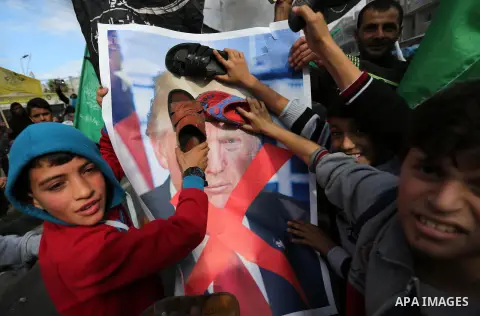 Palestinians hit with slippers a poster depicting U.S. President Donald Trump during a protest against US President Donald Trump's decision to recognise Jerusalem as the capital of Israel, in al-Bureij in the central of...