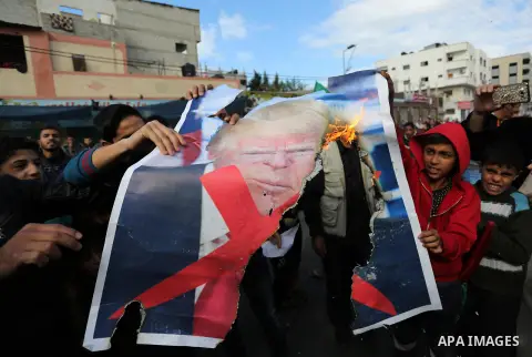 Palestinians burn posters depicting U.S. President Donald Trump during a protest against US President Donald Trump's decision to recognise Jerusalem as the capital of Israel, in al-Bureij in the central of Gaza strip, on...
