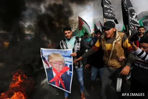 Palestinians burn posters depicting U.S. President Donald Trump during a protest against US President Donald Trump's decision to recognise Jerusalem as the capital of Israel, in al-Bureij in the central of Gaza strip, on...