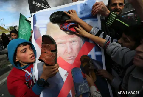Palestinians hit with slippers a poster depicting U.S. President Donald Trump during a protest against US President Donald Trump's decision to recognise Jerusalem as the capital of Israel, in al-Bureij in the central of...