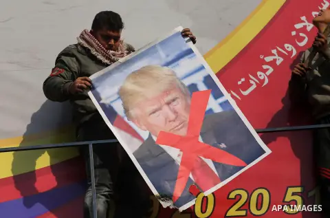 Palestinians burn posters depicting U.S. President Donald Trump during a protest against US President Donald Trump's decision to recognise Jerusalem as the capital of Israel, in al-Bureij in the central of Gaza strip, on...