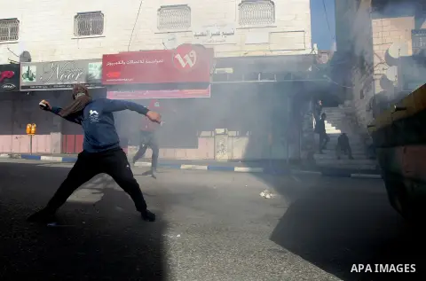 Palestinian protesters hurl stones towadrs Israeli security forces during clashes in the city centre of the occupied West Bank town of Hebron on December 15, 2017 as demonstrations continue to flare in the Middle East an...