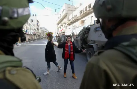 French female protesters hold a bouquet in front of Israeli security forces during a protest in the city centre of the occupied West Bank town of Hebron on December 15, 2017 as demonstrations continue to flare in the Mid...