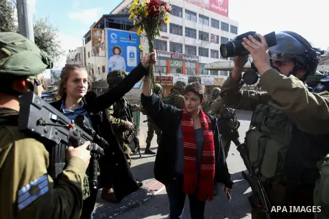 French female protesters hold a bouquet in front of Israeli security forces during a protest in the city centre of the occupied West Bank town of Hebron on December 15, 2017 as demonstrations continue to flare in the Mid...