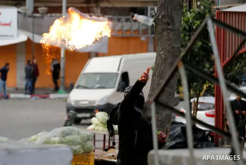 A Palestinian protester throws a molotov cocktail towadrs Israeli security forces during clashes in the city centre of the occupied West Bank town of Hebron on December 15, 2017 as demonstrations continue to flare in the...
