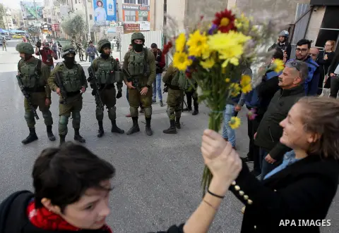 French female protesters hold a bouquet in front of Israeli security forces during a protest in the city centre of the occupied West Bank town of Hebron on December 15, 2017 as demonstrations continue to flare in the Mid...