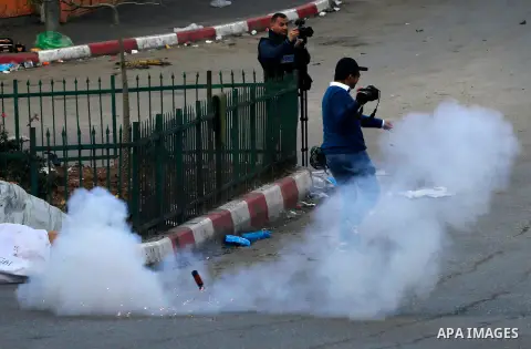 A Palestinian photographer runs for cover from a tear gas canister fired by Israeli security forces during clahes with Palestinian protesters in the city centre of the occupied West Bank town of Hebron on December 15, 20...