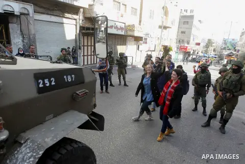 French female protesters hold a bouquet in front of Israeli security forces during a protest in the city centre of the occupied West Bank town of Hebron on December 15, 2017 as demonstrations continue to flare in the Mid...