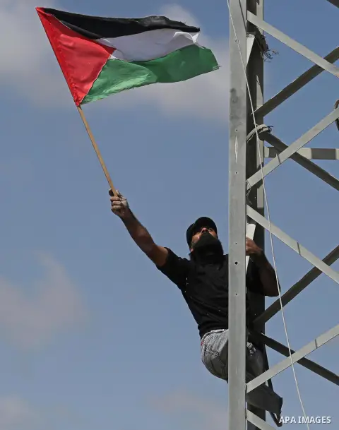 (FILES) This file photo taken on May 19, 2017 shows A Palestinian protester Ibraheem Abu Thuraya, 29, waves a national flag during clashes with Israeli security forces following a protest against the blockade on Gaza Str...