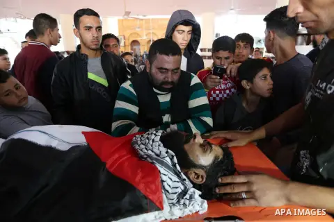 Palestinians peer over the body of 29-year-old Ibrahim Abu Thurayeh as they mourn during his funeral in Gaza City on December 16, 2017 after he was shot dead in clashes between Israeli forces and protesters along the Gaz...