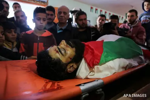 Palestinians peer over the body of 29-year-old Ibrahim Abu Thurayeh as they mourn during his funeral in Gaza City on December 16, 2017 after he was shot dead in clashes between Israeli forces and protesters along the Gaz...