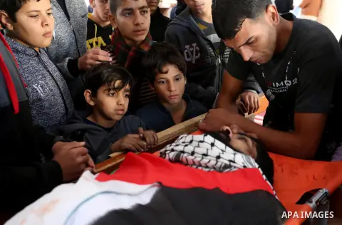 Palestinians peer over the body of 29-year-old Ibrahim Abu Thurayeh as they mourn during his funeral in Gaza City on December 16, 2017 after he was shot dead in clashes between Israeli forces and protesters along the Gaz...