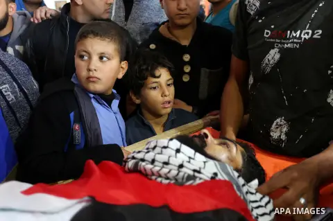 Palestinians peer over the body of 29-year-old Ibrahim Abu Thurayeh as they mourn during his funeral in Gaza City on December 16, 2017 after he was shot dead in clashes between Israeli forces and protesters along the Gaz...