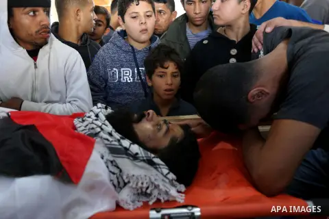Palestinians peer over the body of 29-year-old Ibrahim Abu Thurayeh as they mourn during his funeral in Gaza City on December 16, 2017 after he was shot dead in clashes between Israeli forces and protesters along the Gaz...