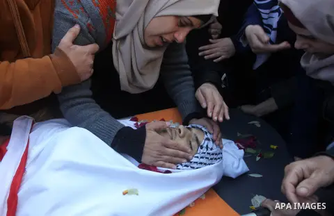 Palestinians gather around the body of Mohammad Aqel, a Palestinian man who was killed after carrying out a stabbing attack on an Israeli soldier, mourn during the funeral of their brother in the village of Beit Ula, nea...