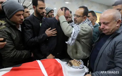 Palestinians gather around the body of Mohammad Aqel, a Palestinian man who was killed after carrying out a stabbing attack on an Israeli soldier, mourn during the funeral of their brother in the village of Beit Ula, nea...