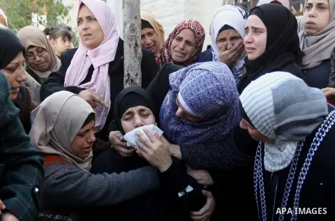 Palestinian relatives mourn on the body of Mohammad Aqel, a Palestinian man who was killed after carrying out a stabbing attack on an Israeli soldier, during the funeral of their brother in the village of Beit Ula, near...