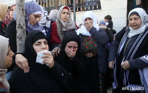 Palestinian relatives mourn on the body of Mohammad Aqel, a Palestinian man who was killed after carrying out a stabbing attack on an Israeli soldier, during the funeral of their brother in the village of Beit Ula, near...