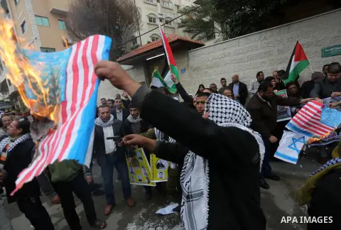 Palestinians burn an Israeli flag and a U.S. flag during a protest against Trump's decision to recognize Jerusalem as the capital of Israel, in front of Red cross office in Gaza city, on December 18, 2017. Photo by Moham...