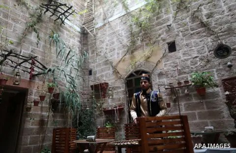A Palestinian waiter wears a traditional costume as he stands at the "Bait Sitty resturant" in the Old Gaza city on December 19, 2017. Bait Sitty resturant is the first archaeological restaurant in the Gaza Strip which w...
