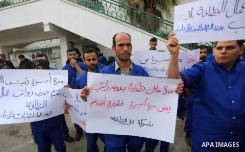 Palestinian cleaners hold banners during a protest to demand their salaries, in Gaza City December 20, 2017. Photo by Mohammed Asad