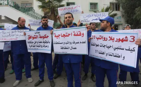 Palestinian cleaners hold banners during a protest to demand their salaries, in Gaza City December 20, 2017. Photo by Mohammed Asad