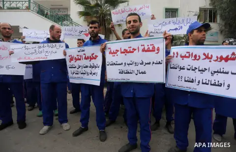 Palestinian cleaners hold banners during a protest to demand their salaries, in Gaza City December 20, 2017. Photo by Mohammed Asad
