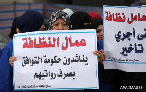 Palestinian cleaners hold banners during a protest to demand their salaries, in Gaza City December 20, 2017. Photo by Mohammed Asad