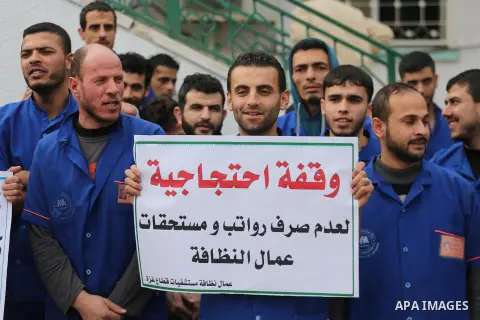 Palestinian cleaners hold banners during a protest to demand their salaries, in Gaza City December 20, 2017. Photo by Mohammed Asad