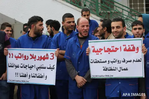 Palestinian cleaners hold banners during a protest to demand their salaries, in Gaza City December 20, 2017. Photo by Mohammed Asad