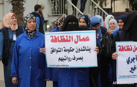 Palestinian cleaners hold banners during a protest to demand their salaries, in Gaza City December 20, 2017. Photo by Mohammed Asad